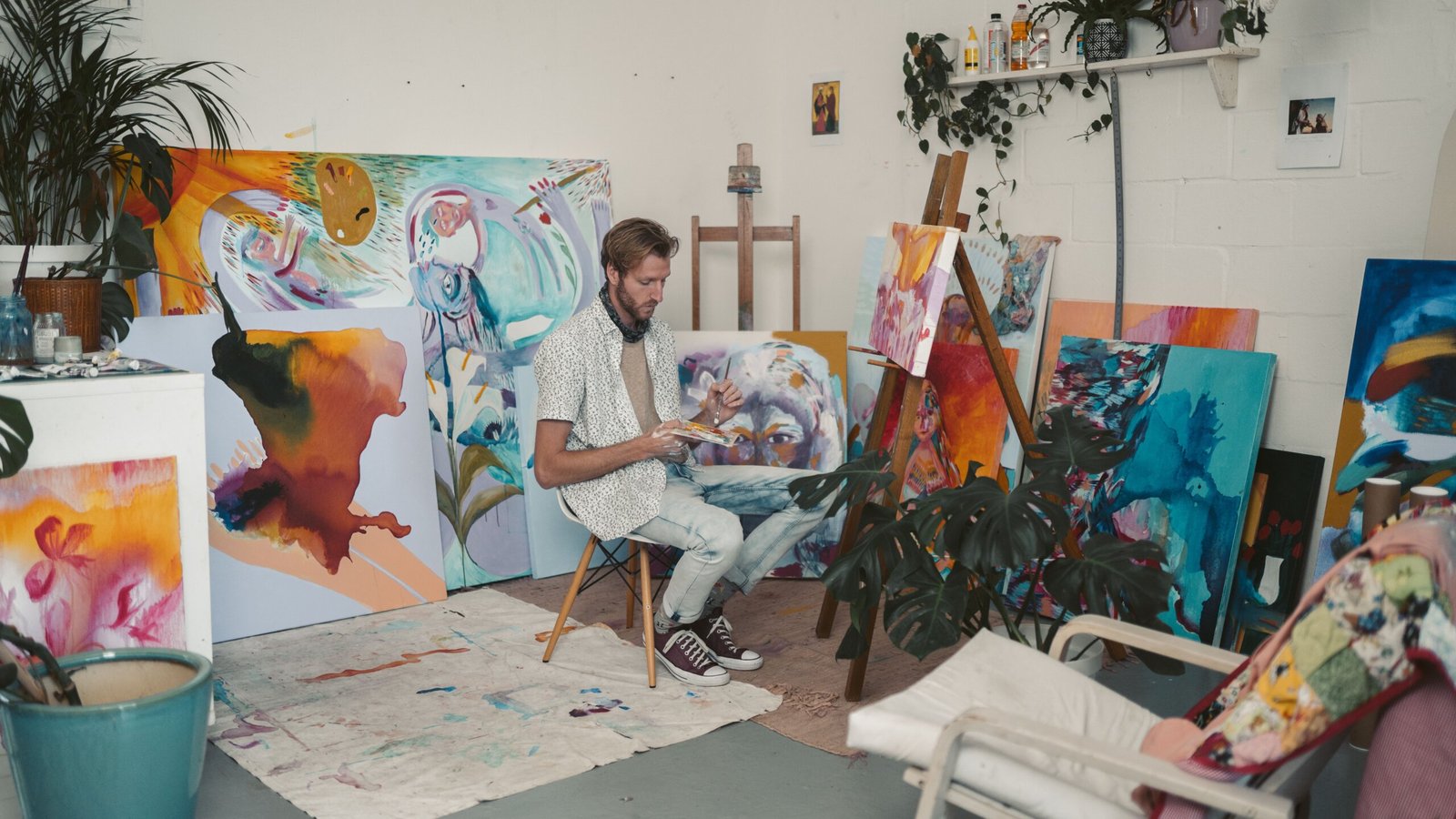 A male artist painting vibrant canvases in a creative studio space.